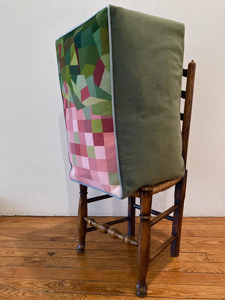 Tall rectangle-shaped needlepoint pillow on a wooden chair