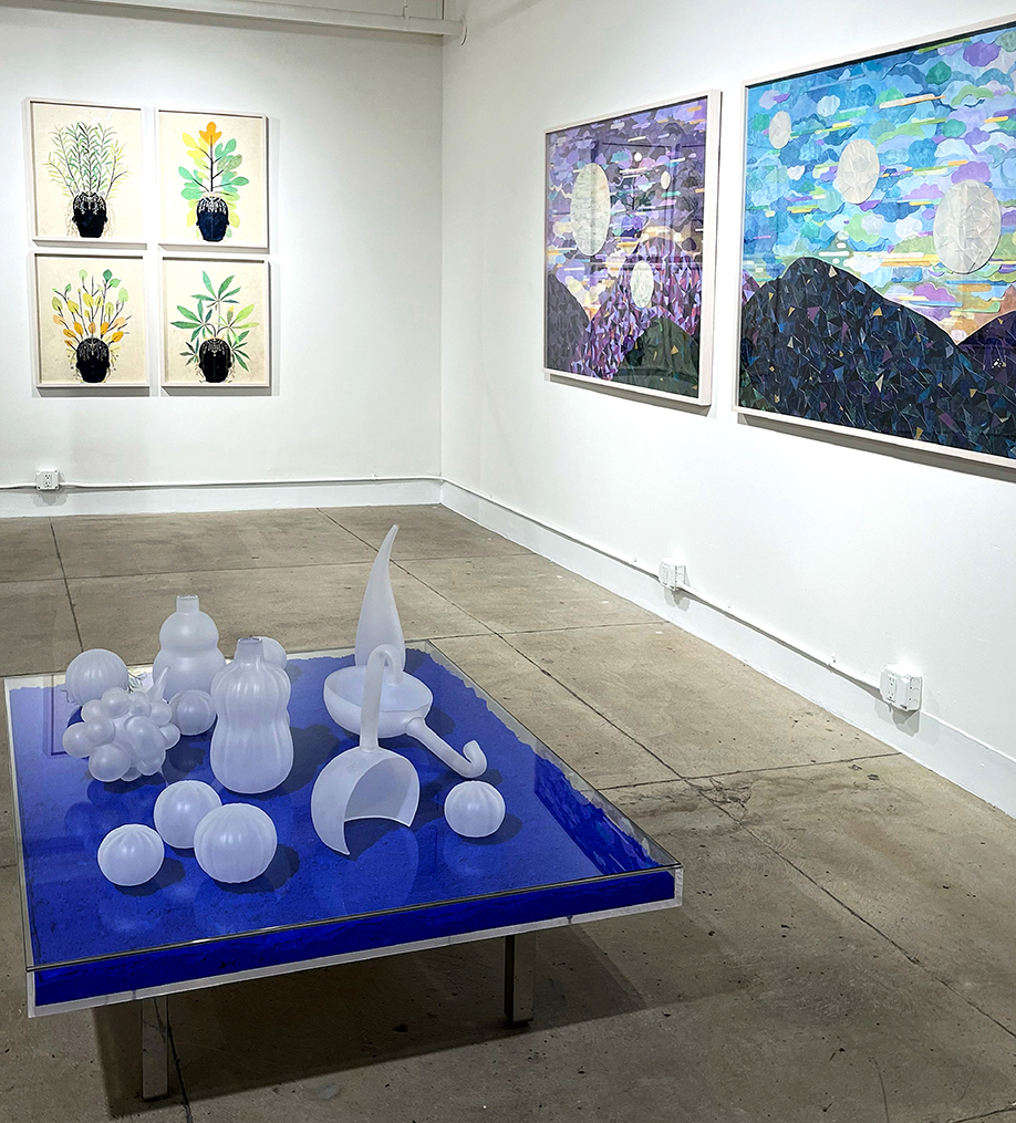 installation view with glasss sculpures on Yves Klein table and framed collages 