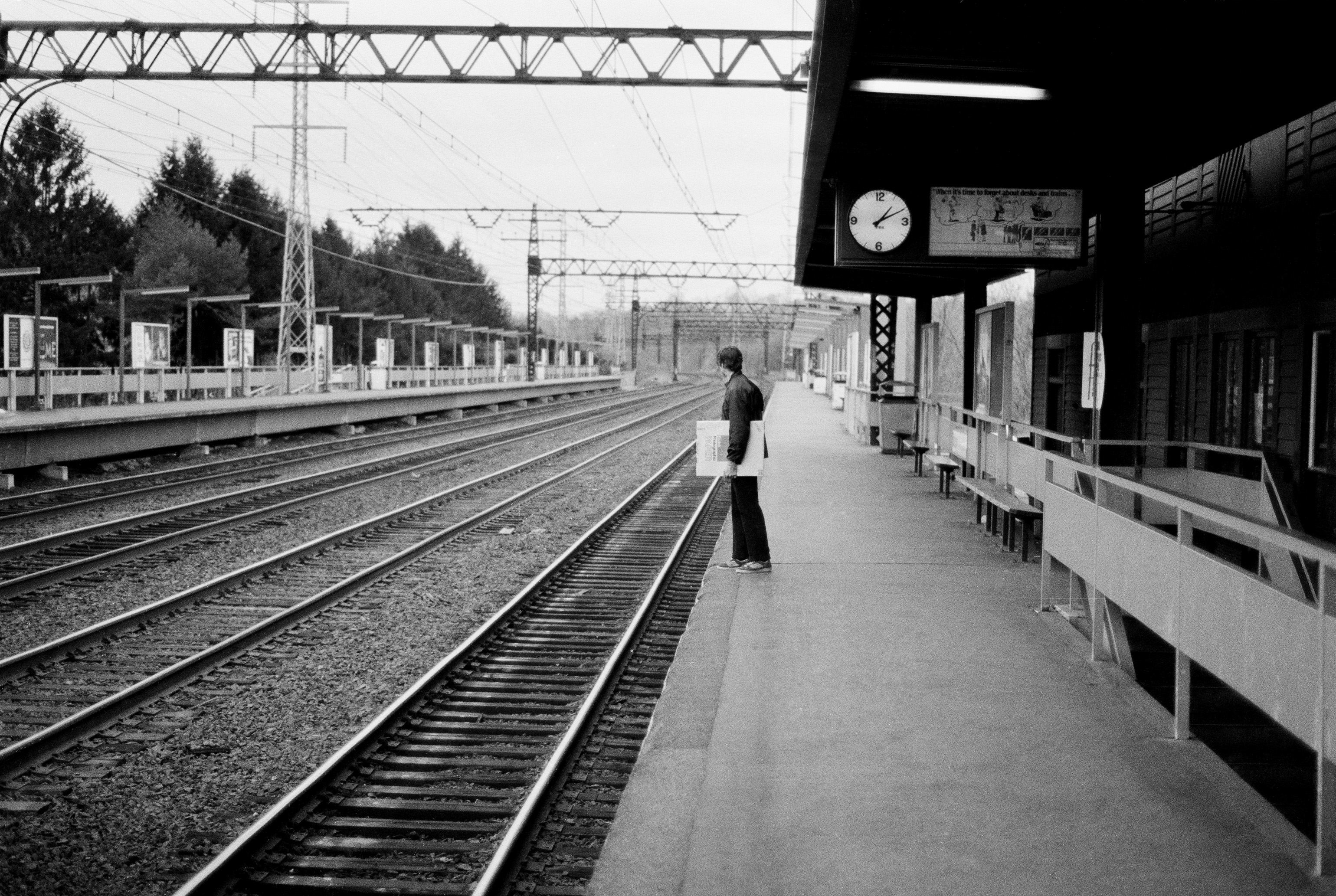 man carrying a box of Kodak paper at a railroad station