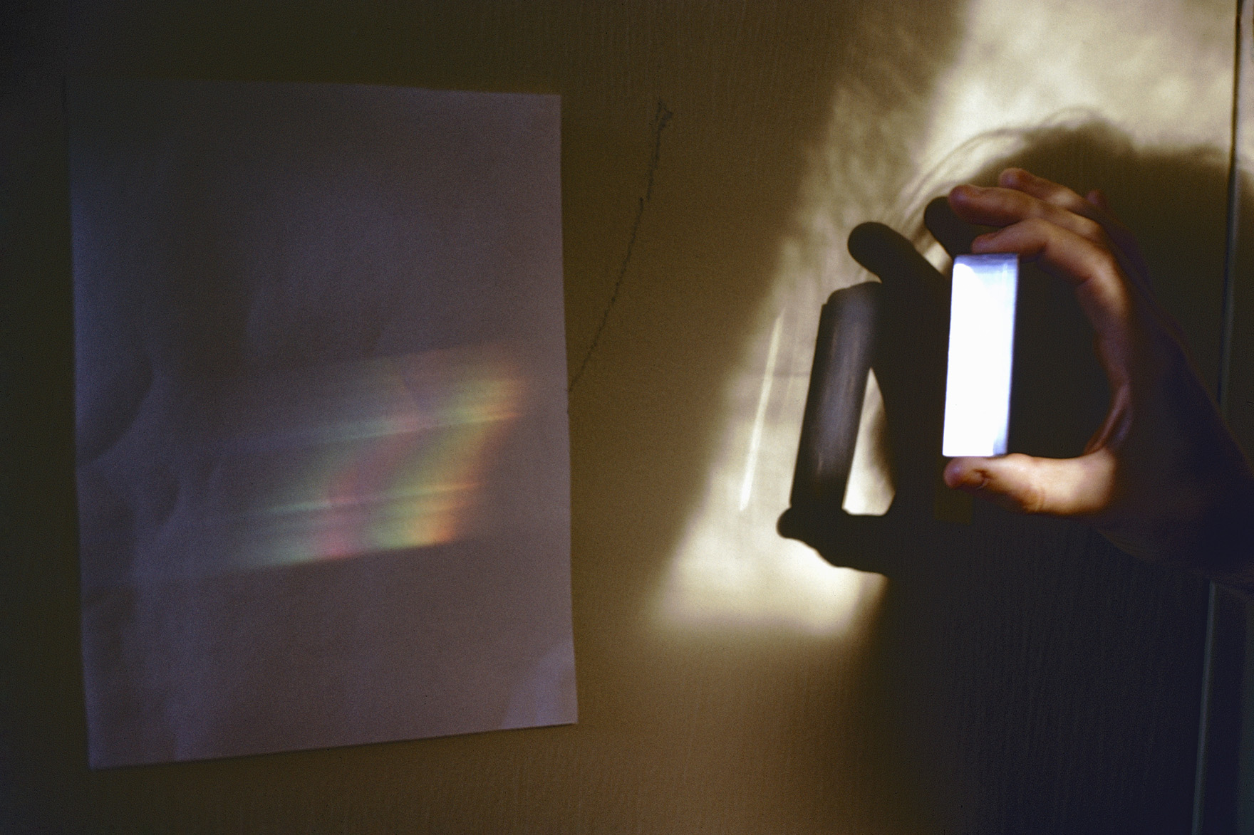 hand holding a prism in front of a sheet of paper